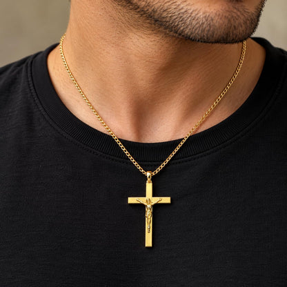 Polished 10K yellow gold Catholic cross pendant resting on dark stone